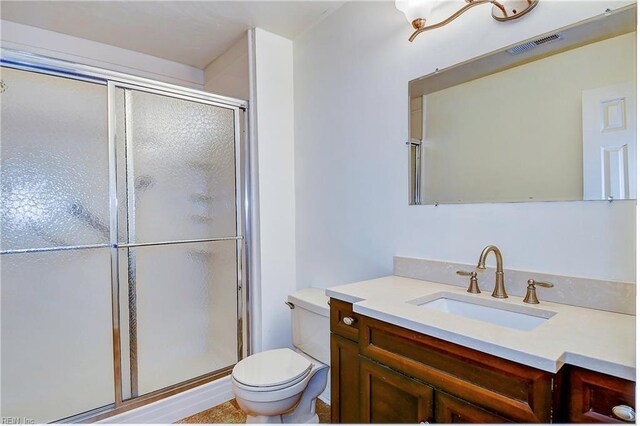 bathroom featuring vanity, toilet, and an enclosed shower