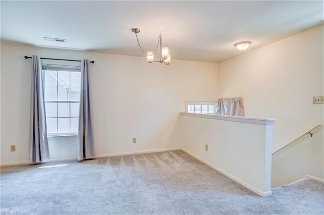 empty room featuring light carpet and a chandelier