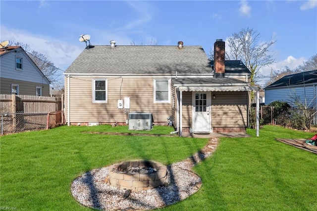 back of house featuring a fire pit, central AC unit, and a lawn