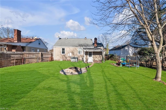 back of house featuring a lawn, central air condition unit, and a trampoline