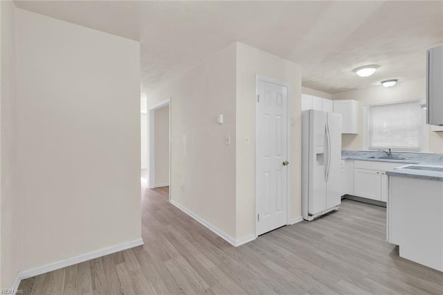 kitchen featuring white cabinets, light wood-type flooring, white fridge with ice dispenser, and sink