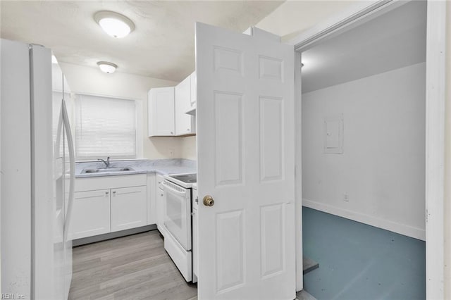 kitchen with white cabinets, light wood-type flooring, white appliances, and sink