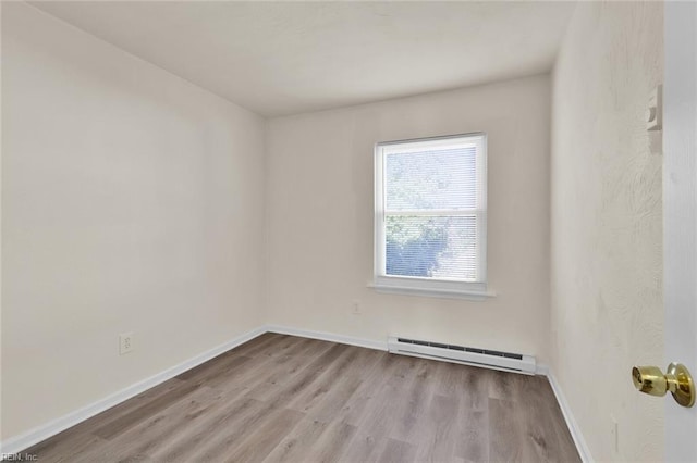 empty room featuring light hardwood / wood-style floors and a baseboard heating unit