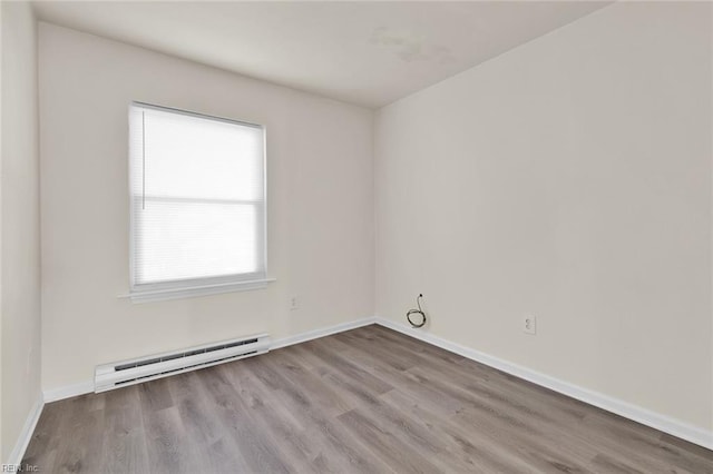 unfurnished room featuring light hardwood / wood-style floors and a baseboard heating unit