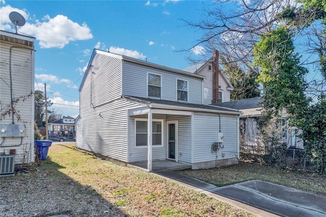 rear view of house featuring a lawn and central AC unit