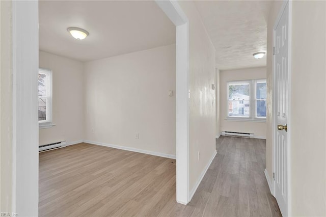 hallway featuring plenty of natural light, light hardwood / wood-style floors, and baseboard heating