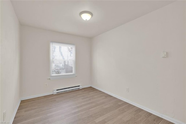 unfurnished room featuring light wood-type flooring and a baseboard heating unit