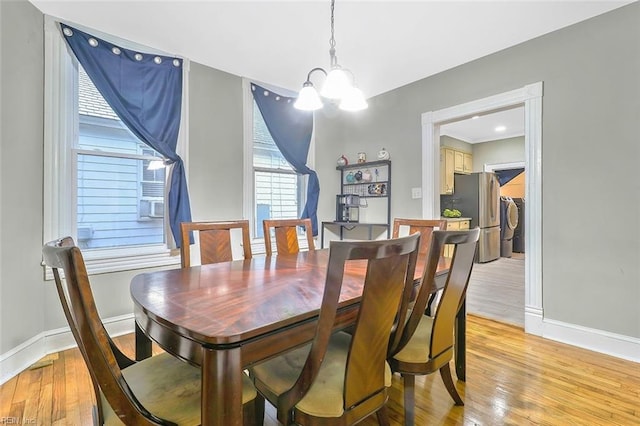 dining space featuring a chandelier, separate washer and dryer, and light hardwood / wood-style flooring