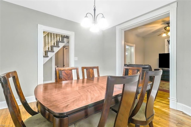 dining room with ceiling fan with notable chandelier and light wood-type flooring