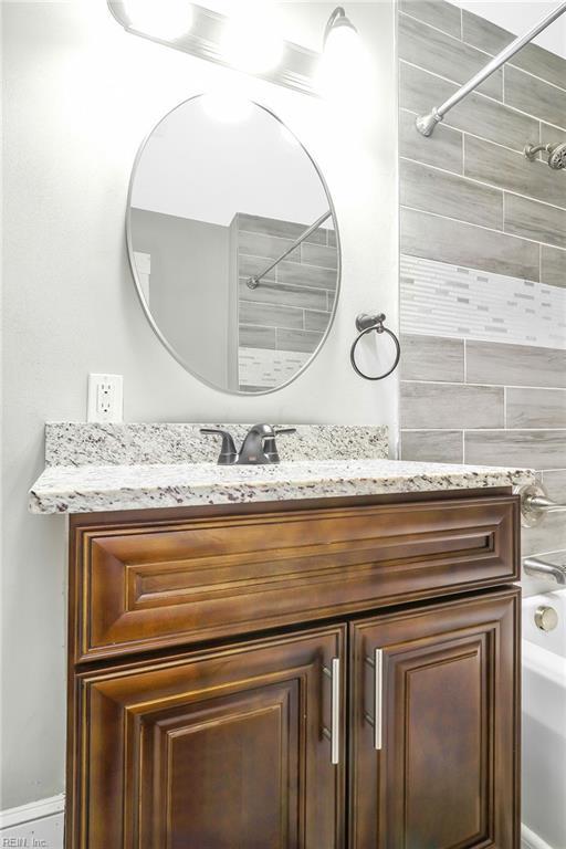 bathroom with tiled shower / bath combo and vanity