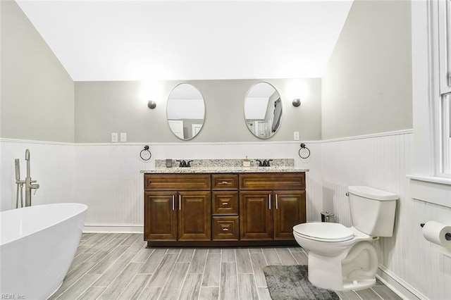 bathroom featuring vanity, toilet, wood-type flooring, and a tub to relax in