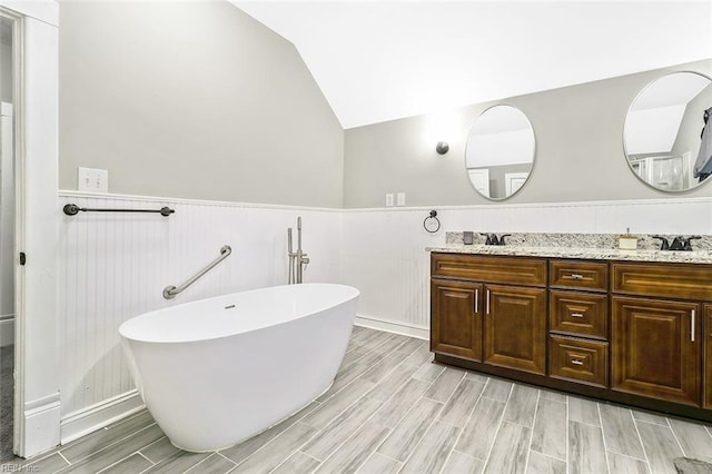 bathroom featuring a washtub, vanity, and vaulted ceiling