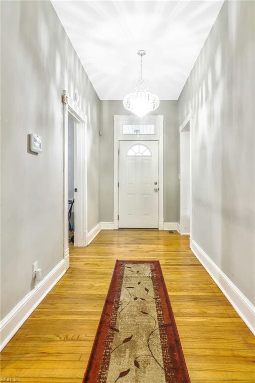 entryway with hardwood / wood-style flooring and a notable chandelier