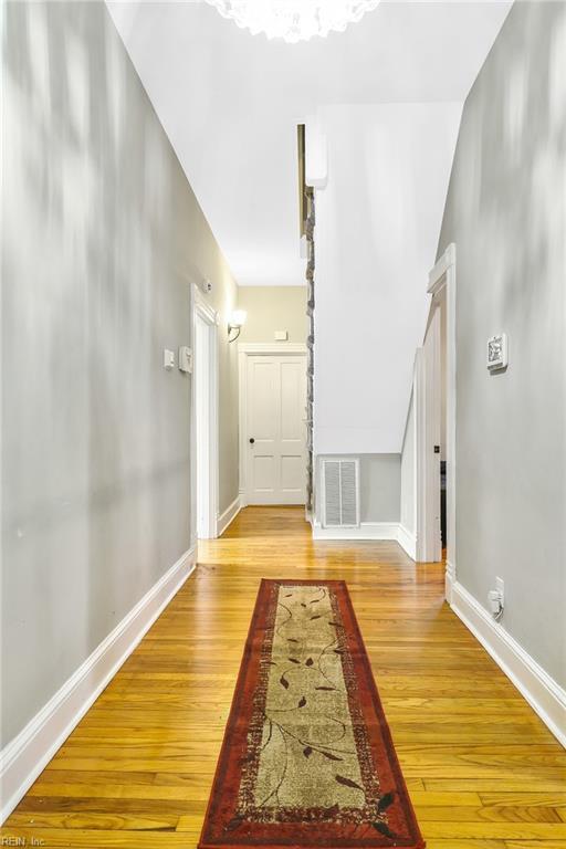 corridor with light hardwood / wood-style floors and vaulted ceiling