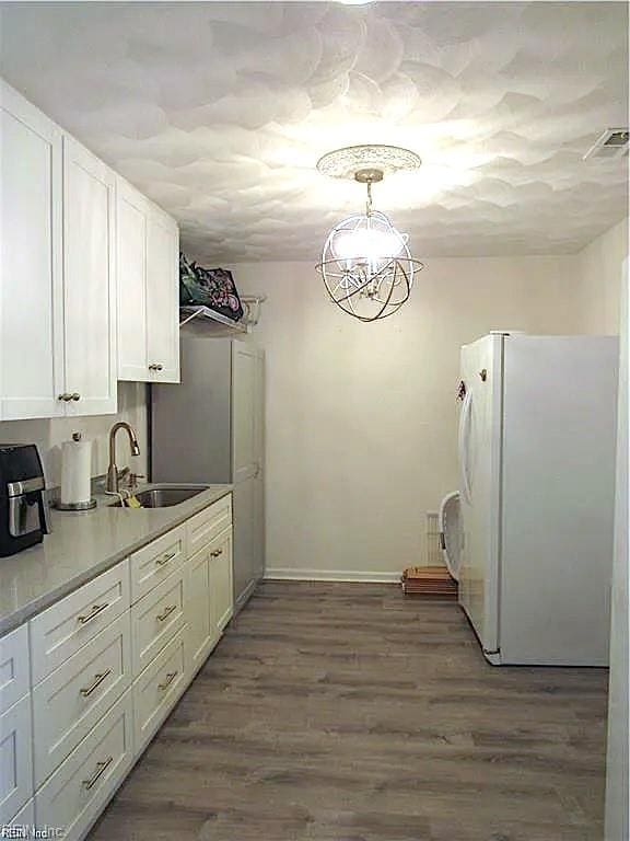 kitchen with white cabinets, white refrigerator, light hardwood / wood-style flooring, and sink