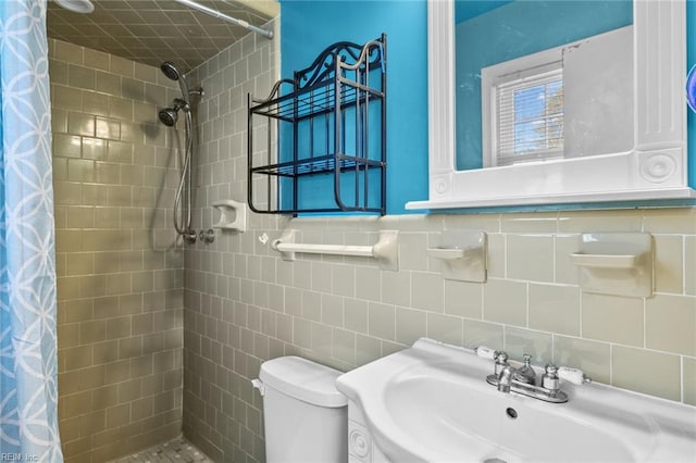 bathroom featuring toilet, tile walls, curtained shower, and sink