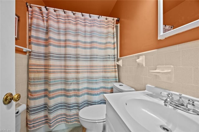 full bathroom featuring vanity, toilet, shower / bath combo with shower curtain, and tile walls