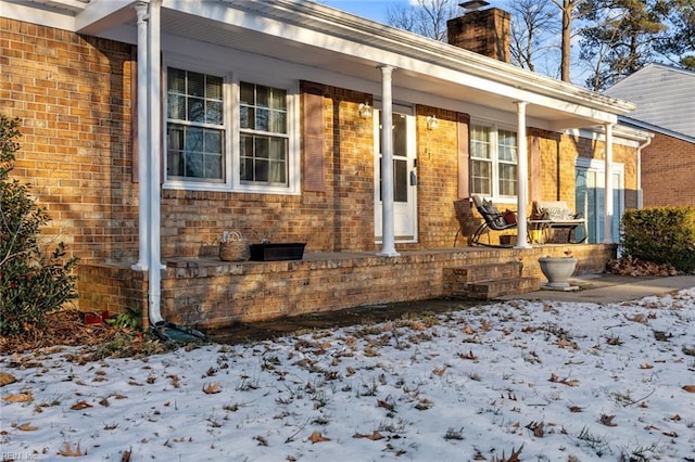 snow covered property entrance with a porch