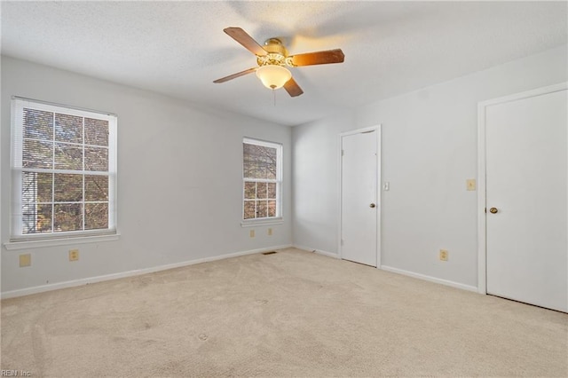 carpeted spare room featuring a wealth of natural light and ceiling fan