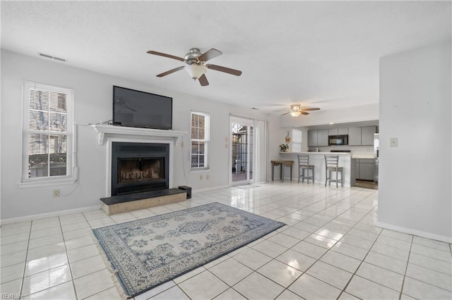 unfurnished living room featuring ceiling fan and light tile patterned floors