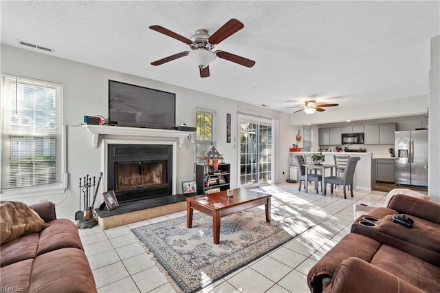 tiled living room with ceiling fan and a textured ceiling