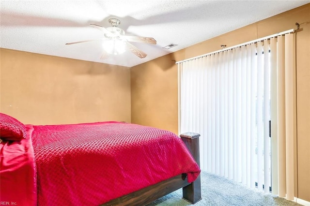 carpeted bedroom featuring ceiling fan and a textured ceiling