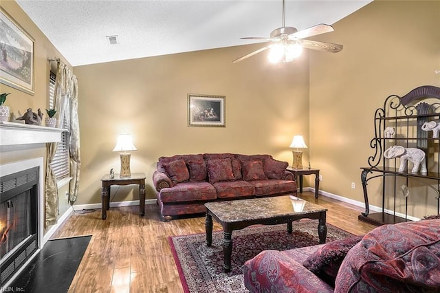 living room with a textured ceiling, ceiling fan, light hardwood / wood-style floors, and lofted ceiling