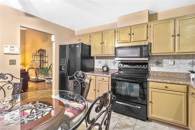 kitchen featuring black appliances, decorative backsplash, light tile patterned floors, light brown cabinetry, and light stone counters