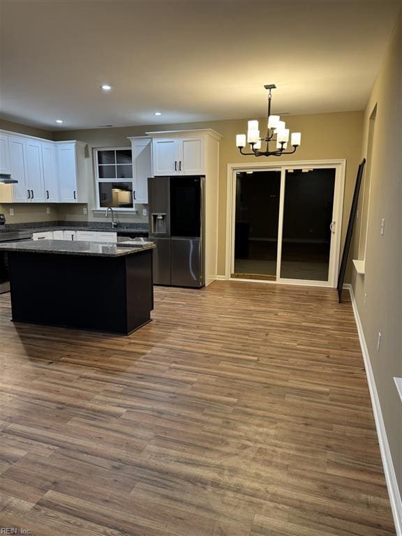 kitchen with white cabinets, dark stone countertops, appliances with stainless steel finishes, a kitchen island, and a chandelier