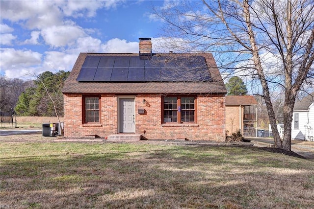 view of front facade with solar panels, central AC unit, and a front lawn