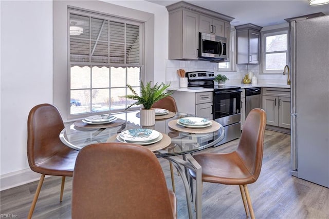 kitchen with backsplash, sink, light hardwood / wood-style flooring, gray cabinets, and appliances with stainless steel finishes