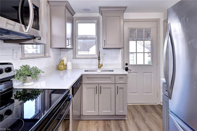 kitchen featuring gray cabinetry, sink, tasteful backsplash, a healthy amount of sunlight, and stainless steel appliances