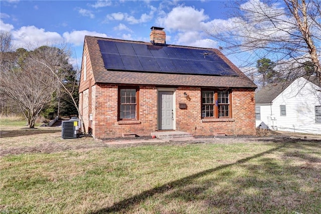 back of house with solar panels, cooling unit, and a lawn