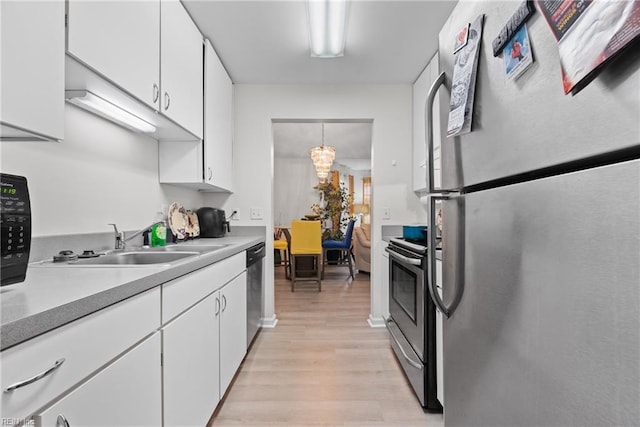 kitchen with stainless steel appliances, sink, a chandelier, light hardwood / wood-style floors, and white cabinetry