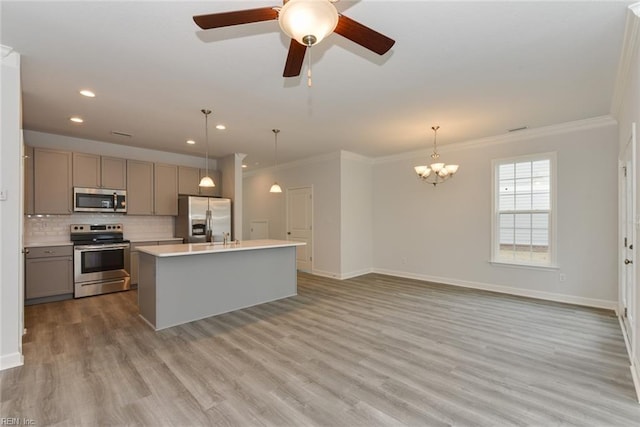 kitchen featuring decorative light fixtures, a center island with sink, appliances with stainless steel finishes, and gray cabinetry