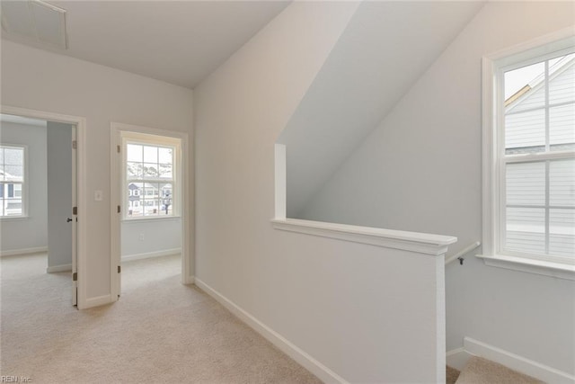 hallway featuring vaulted ceiling and light carpet