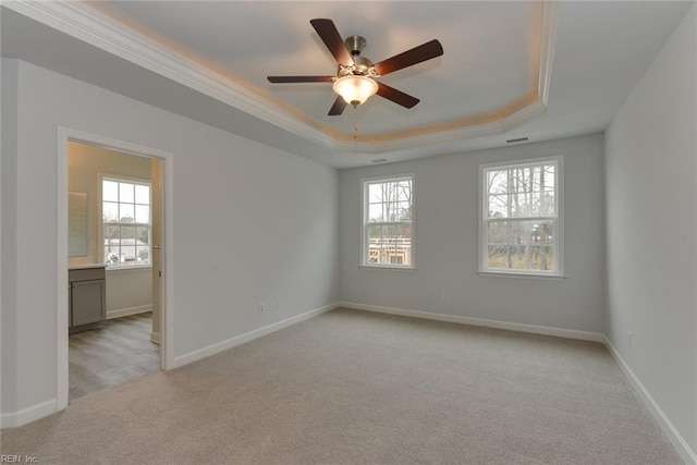 spare room featuring ornamental molding, ceiling fan, a tray ceiling, and light carpet