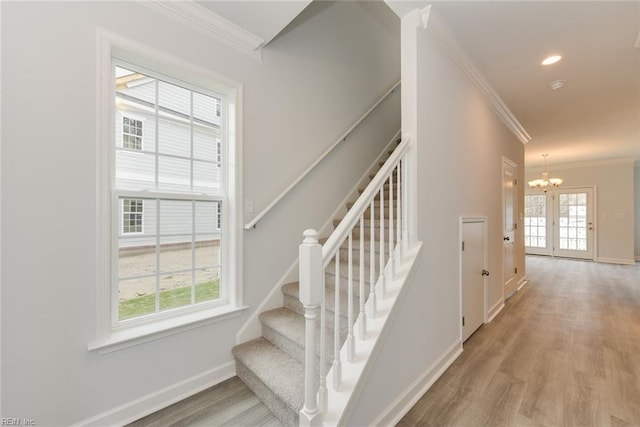 staircase featuring hardwood / wood-style flooring, an inviting chandelier, and crown molding