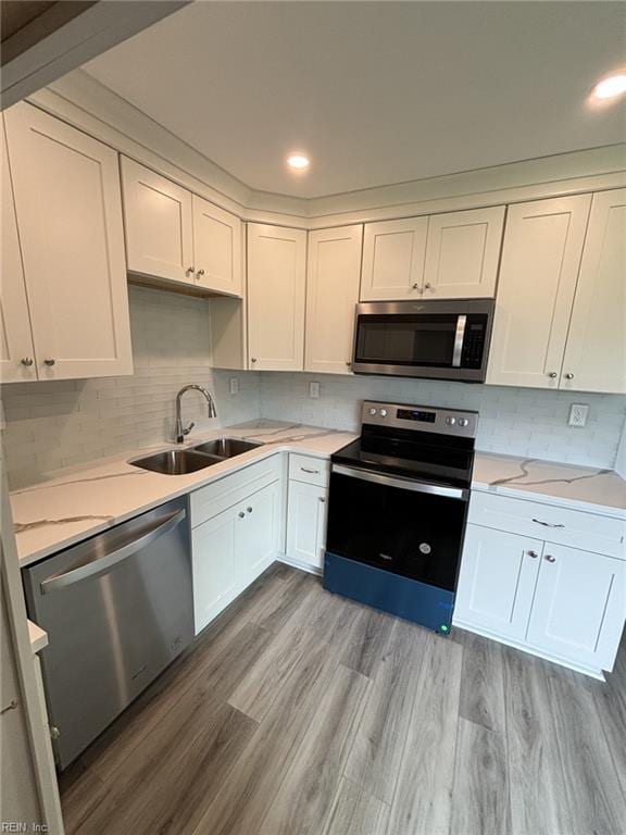 kitchen featuring white cabinetry, sink, tasteful backsplash, appliances with stainless steel finishes, and light wood-type flooring