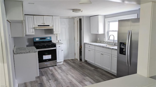 kitchen featuring sink, light stone countertops, appliances with stainless steel finishes, white cabinetry, and wood-type flooring