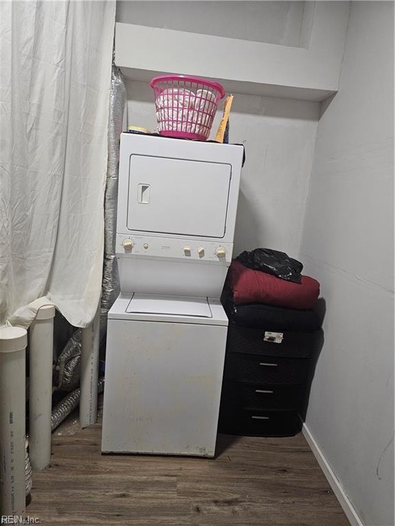 clothes washing area featuring dark hardwood / wood-style flooring and stacked washing maching and dryer