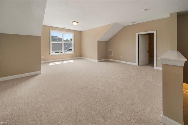 additional living space featuring light colored carpet and vaulted ceiling