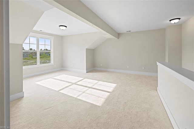 additional living space featuring lofted ceiling with beams and light colored carpet