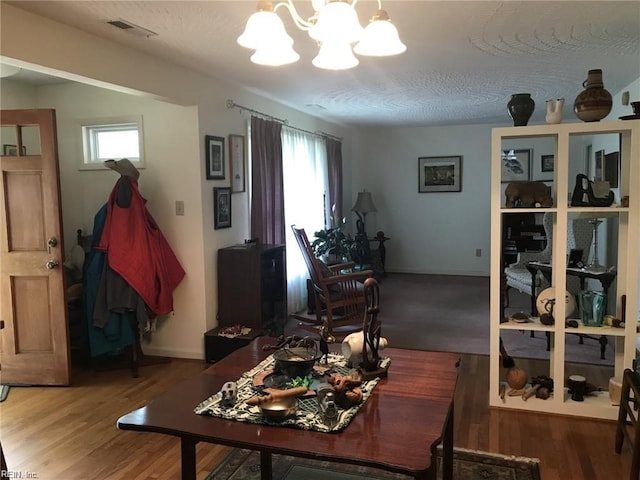 dining area with plenty of natural light, hardwood / wood-style floors, and an inviting chandelier