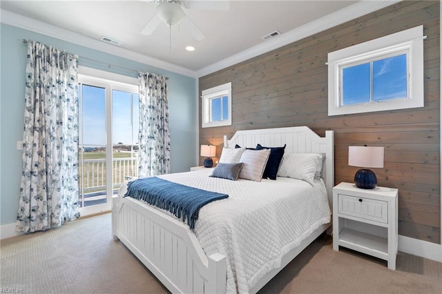 carpeted bedroom with ceiling fan, wood walls, ornamental molding, and access to outside