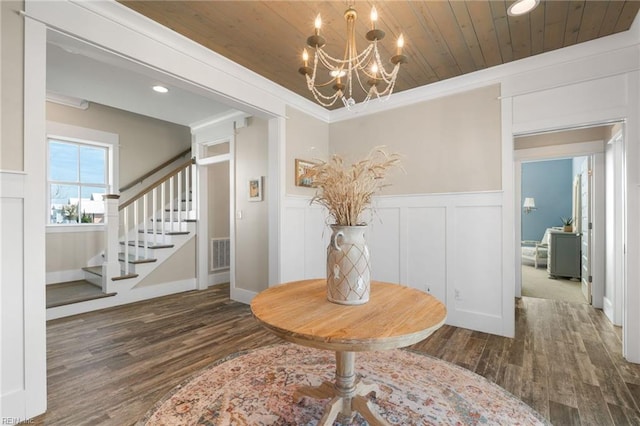 entrance foyer featuring wooden ceiling, dark hardwood / wood-style flooring, ornamental molding, and an inviting chandelier