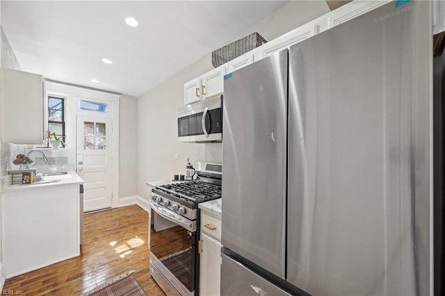 kitchen featuring white cabinets, sink, hardwood / wood-style floors, and appliances with stainless steel finishes