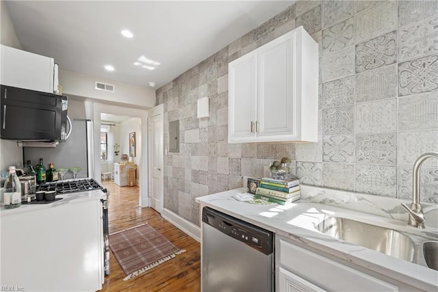 kitchen featuring sink, stainless steel dishwasher, white cabinetry, light stone counters, and wood-type flooring