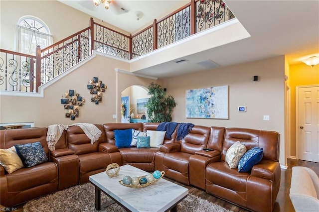 living room featuring hardwood / wood-style flooring, ceiling fan, and a high ceiling