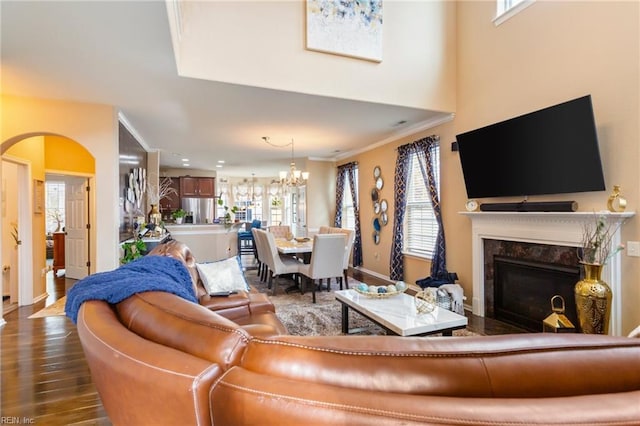 living room with hardwood / wood-style flooring, a premium fireplace, a wealth of natural light, and an inviting chandelier